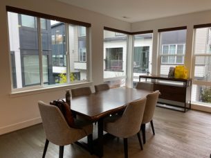 Modern dining area with large windows and elegant chairs, showcasing a clean and organized space after recurring cleaning service by bellevuecleans in Bellevue.