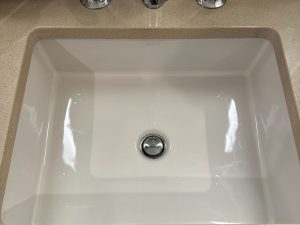 Spotless white sink with polished chrome faucets on a clean beige countertop, professionally maintained by BellevueCleans — expert cleaning services in Bellevue.