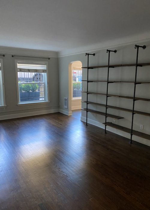 Bright, freshly cleaned living room with hardwood floors and wall shelving, serviced by BellevueCleans — trusted cleaning services in Bellevue, WA.